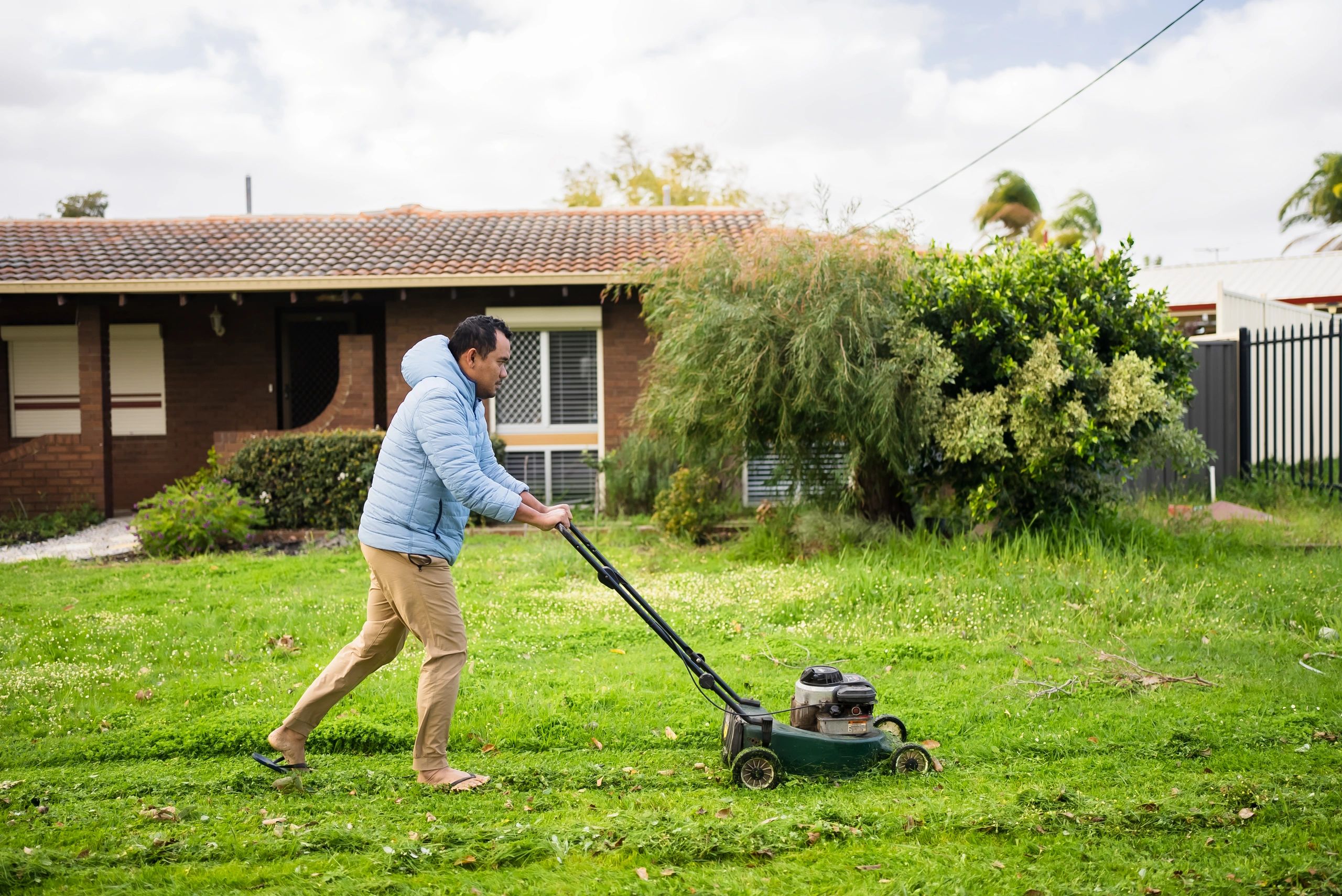 Professional mowing a lawn in a backyard